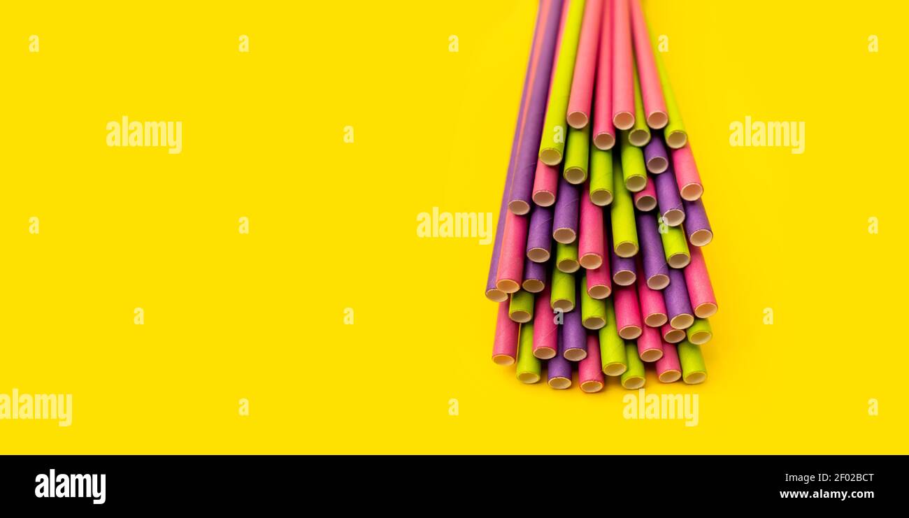 Papier Strohhalme in verschiedenen Farben auf einem hellen gelben Hintergrund. Kreatives modernes Layout Stockfoto