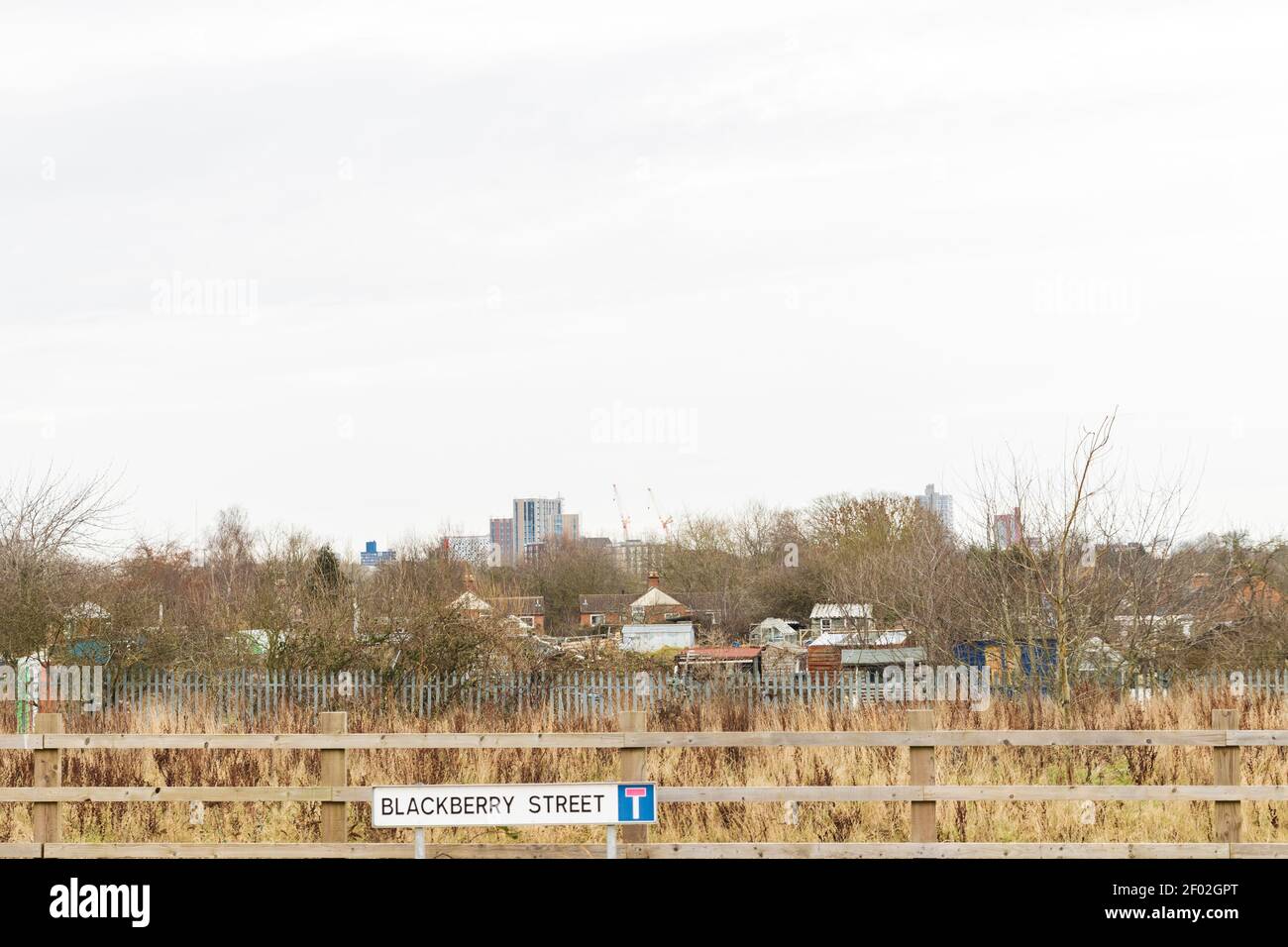 Strauch, Schotterplätze, Stahlzaun, Schuppen und dann die wichtigsten hohen Gebäude in Leicester University am Horizont. Zeigt die Skyline des Stadtzentrums von Leicester. Stockfoto