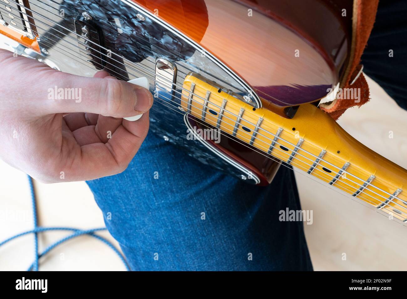 Nahaufnahme Vertikale Ansicht Blick auf einen Mann zu Hause Spielen einer Fender Telecaster Modern Player E-Gitarre mit einem Kunststoffpicker Stockfoto