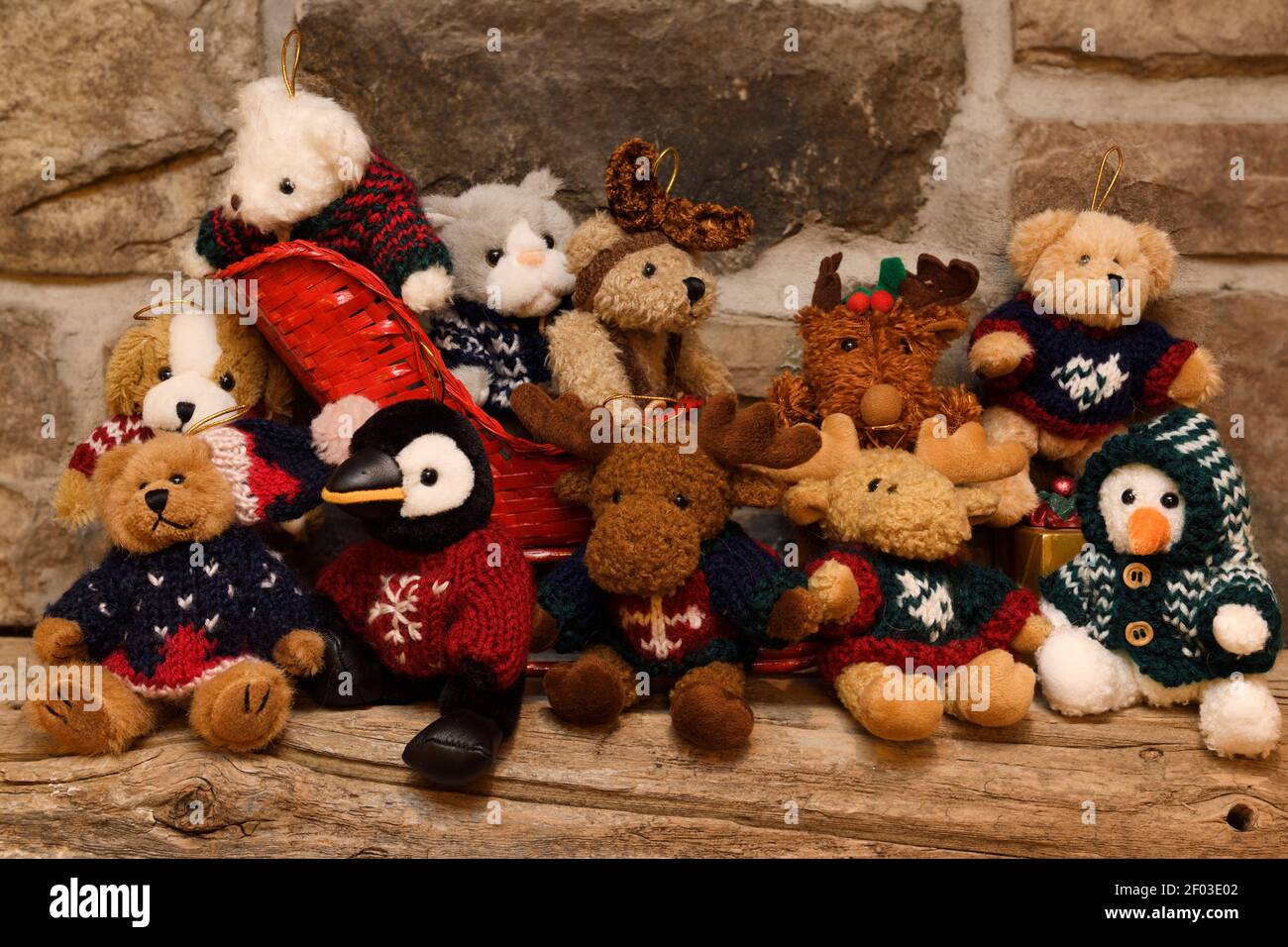 Pelzige gefüllte Teddy Tierspielzeug mit Strickpullover und Schlitten Auf Scheune Balken Mantel und Stein Kamin Stockfoto
