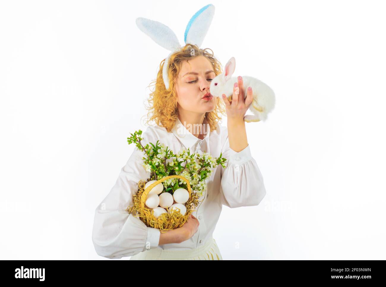 Schöne junge Frau küssen weißen Kaninchen. Nettes Mädchen am Ostertag. Jagt nach Ostereiern. Stockfoto