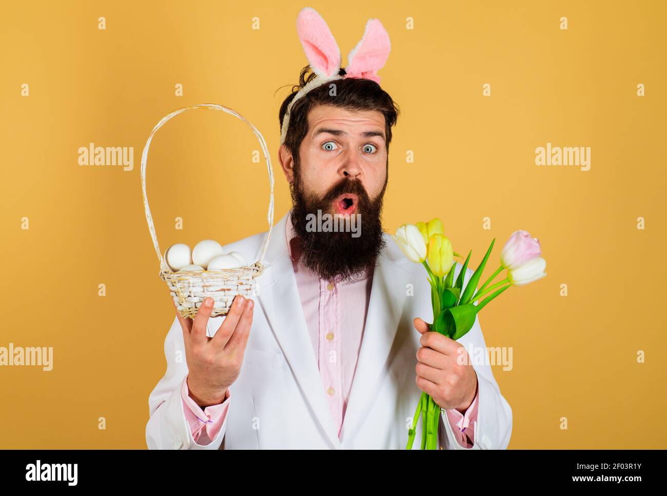 Überrascht Mann in Hasen Ohren mit Korb Ei und Frühlingsblumen. Osterferien. Stockfoto