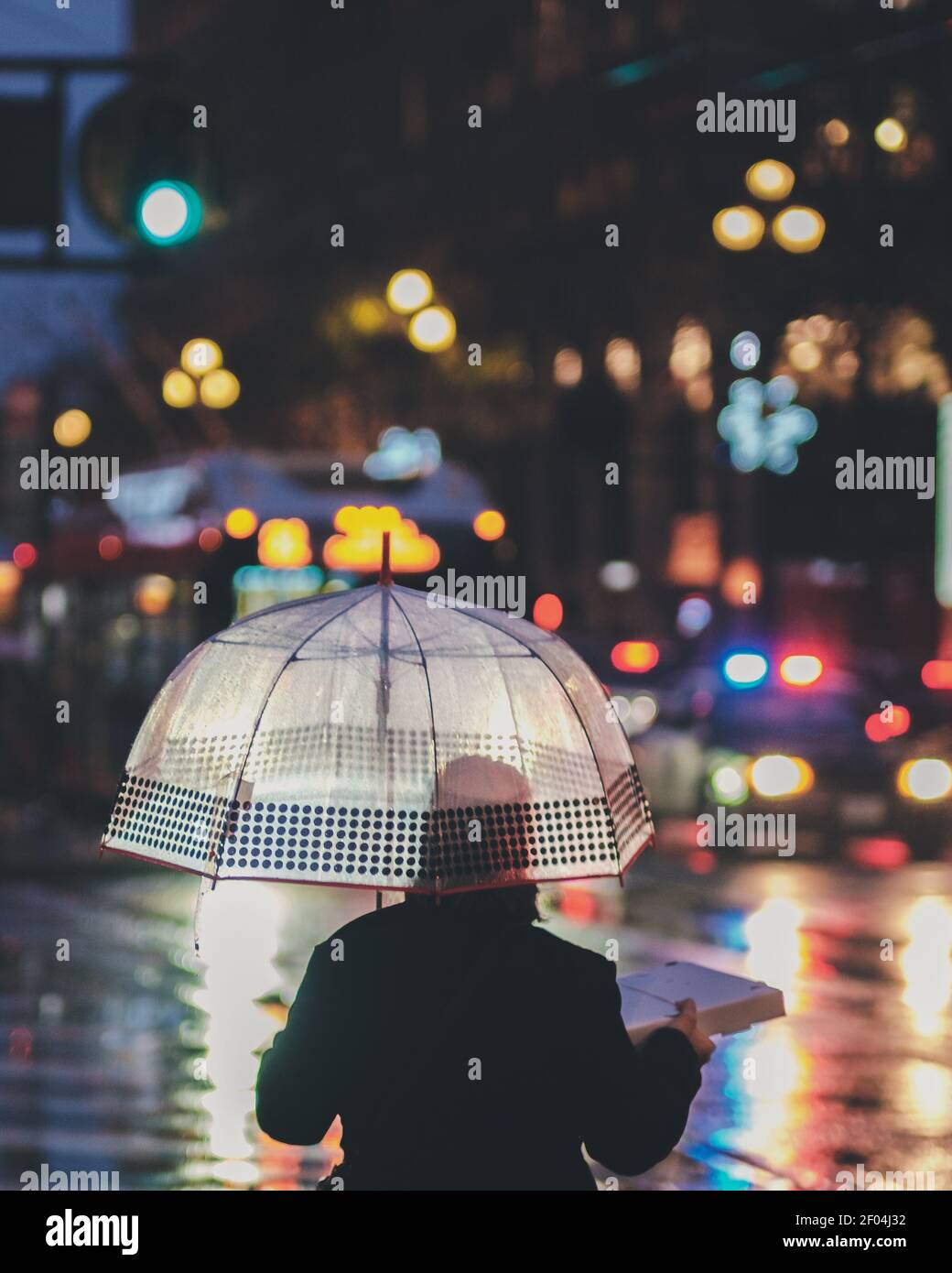 Eine vertikale Aufnahme einer Person, die unter einem Regenschirm steht An einem regnerischen Tag Stockfoto