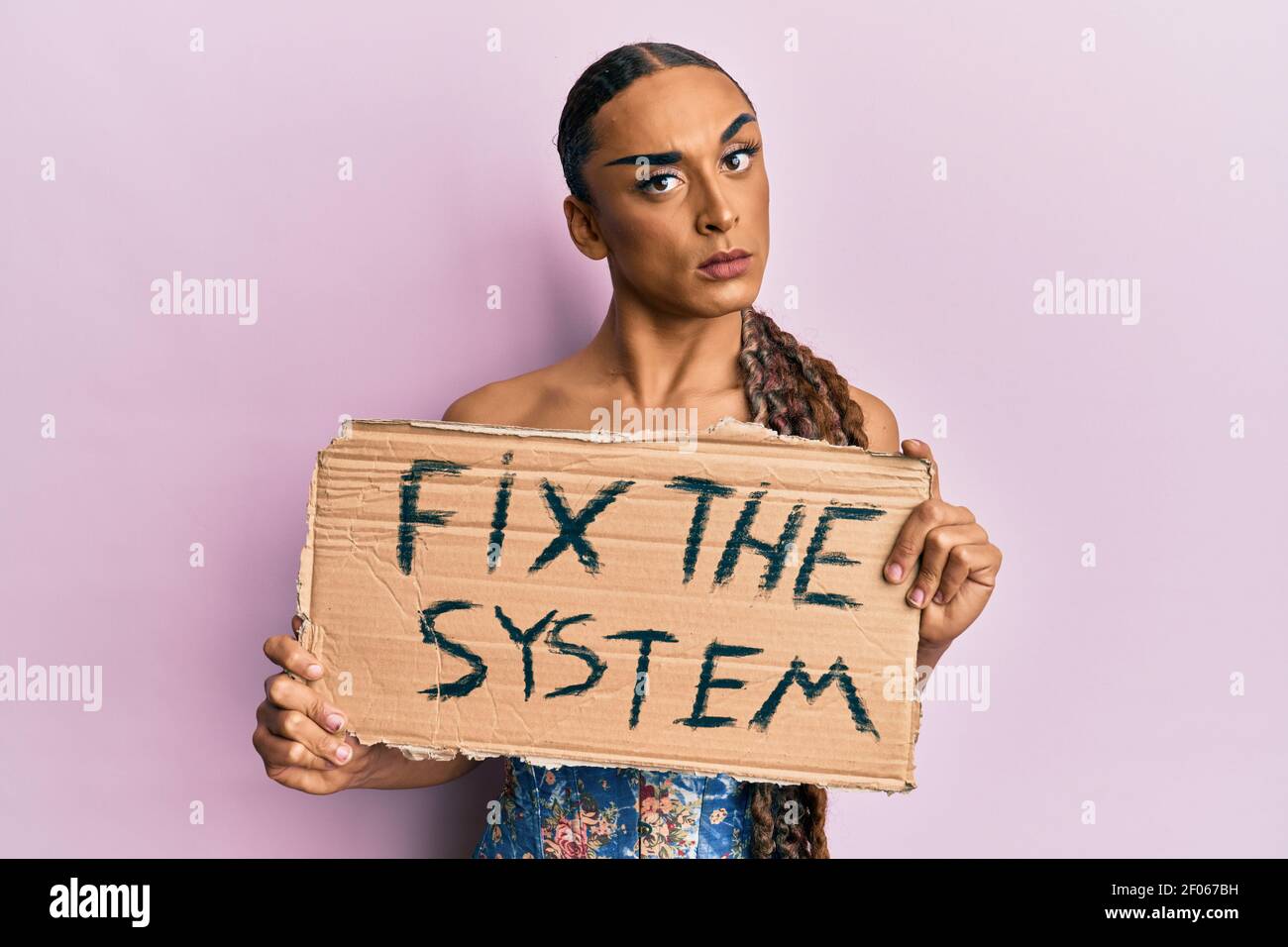 Hispanic Mann trägt Make-up und lange Haare halten fix das System Banner Karton skeptisch und nervös, runzelte wegen des Problems. Negative pe Stockfoto