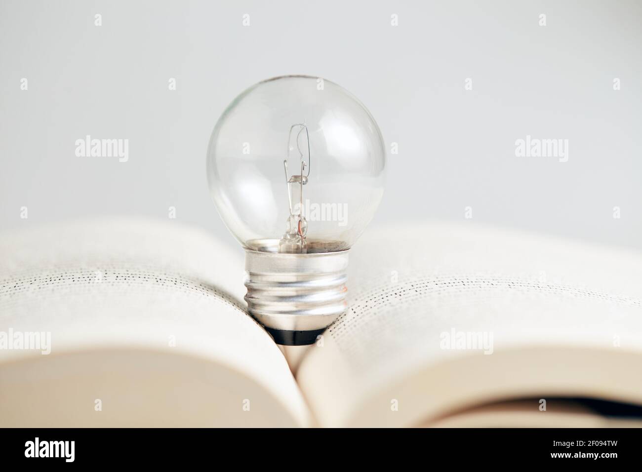 Nahaufnahme einer Glühbirne auf dem geöffneten Buch. Kreatives und pädagogisches Konzept. Stockfoto