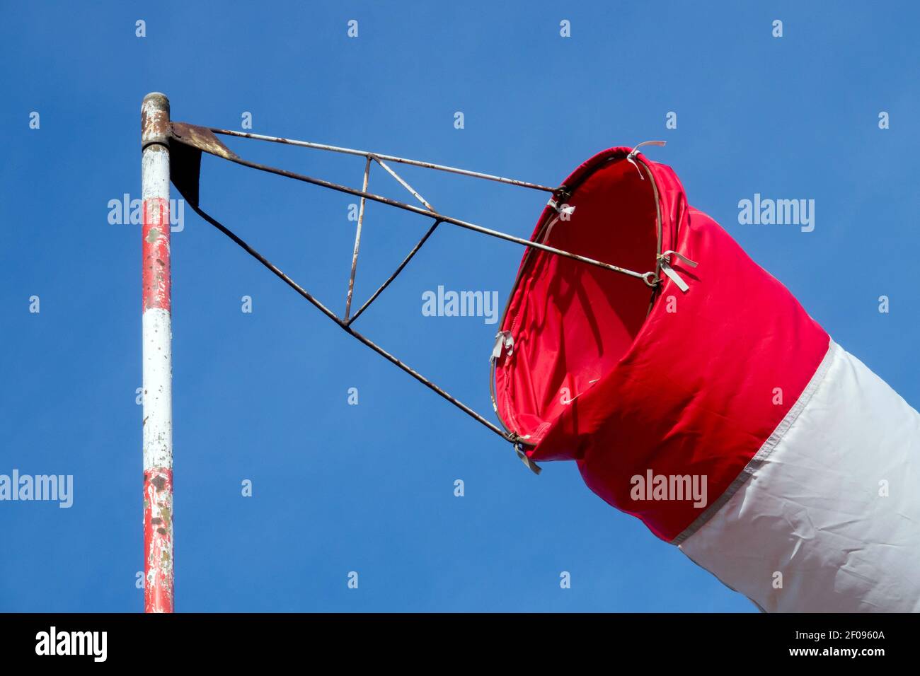 Windsocke mit Nahaufnahme, Luftschlauch auf gestreiftem Stab gegen blaue Windsocke Stockfoto