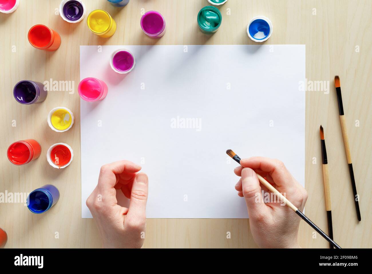 Hände halten Pinsel bereit, Schmerzen mit farbigen Farben auf leerem Papier am Tisch. Kunst und Kreativität Konzept. Stockfoto