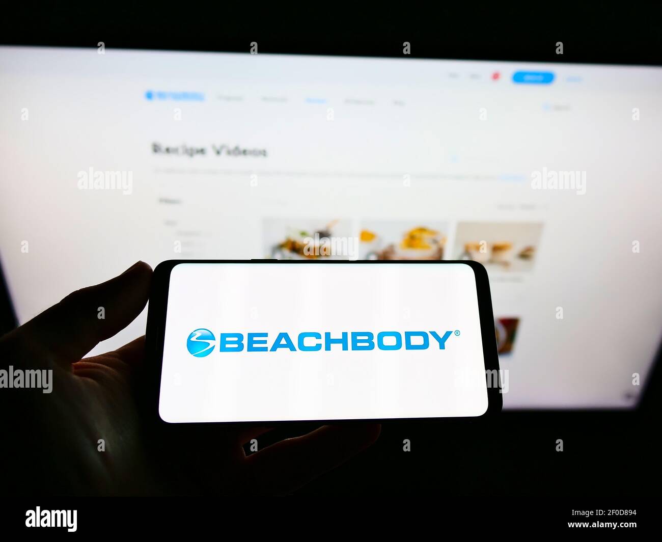 Person hält Smartphone mit Logo der amerikanischen Fitness-und Medienunternehmen Beachbody LLC auf dem Bildschirm vor der Webseite. Fokus auf Handy-Display. Stockfoto