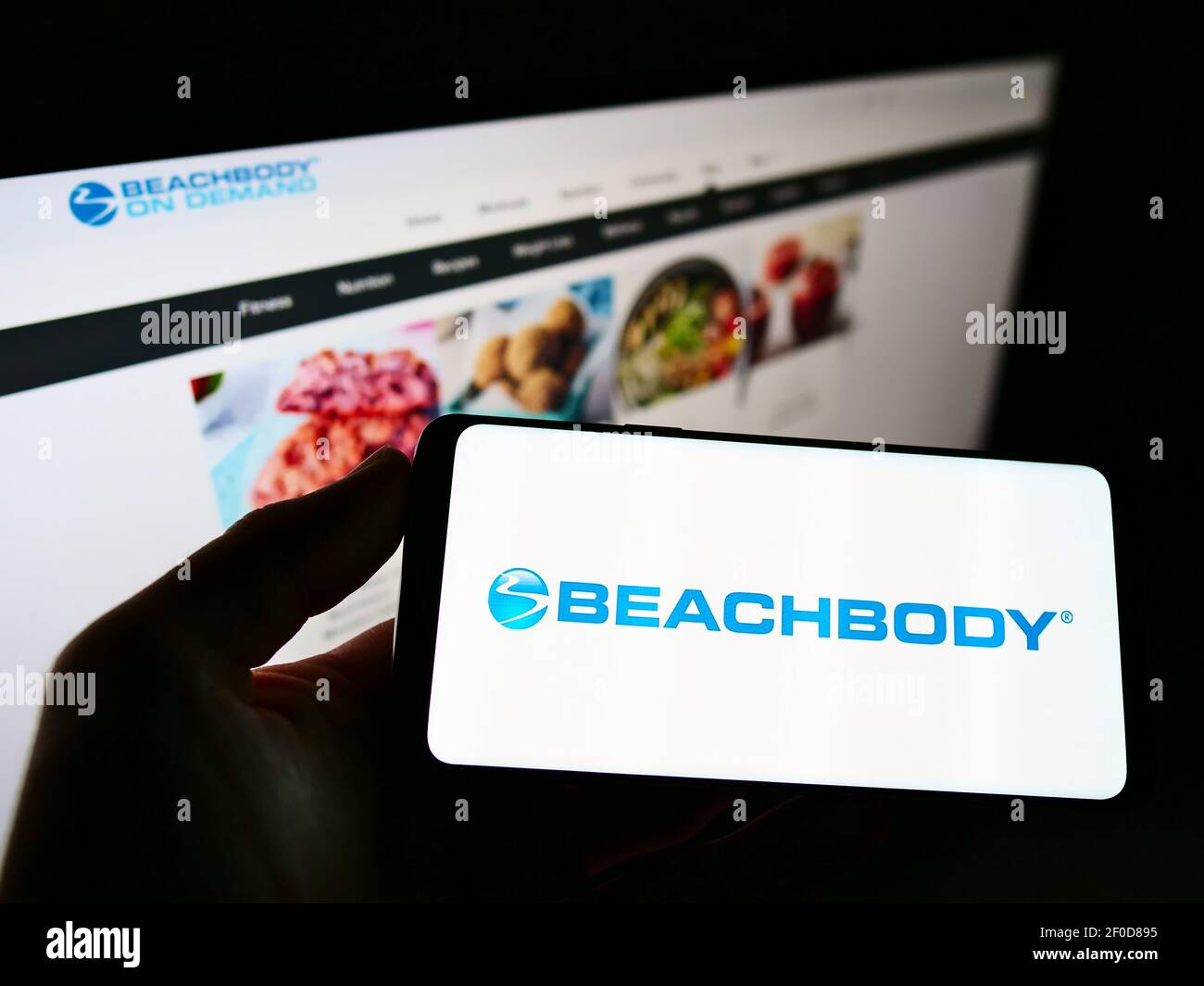 Person hält Handy mit Logo der US-Fitness-und Medienunternehmen Beachbody LLC auf dem Bildschirm vor der Business-Webseite. Konzentrieren Sie sich auf die Telefonanzeige. Stockfoto
