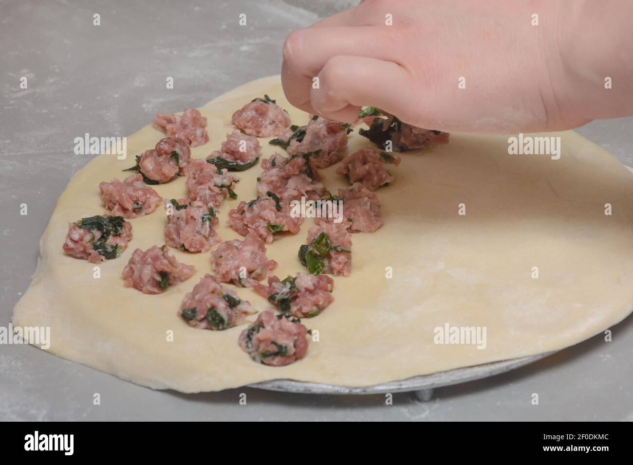 Kochen Sie hausgemachte Knödel mit Hackfleisch und Gewürzen. Teig auf spezielle Form zum Sculpting Ravioli. Nahaufnahme der Hand des Kochs, selektiver Fokus. Stockfoto Kochen Sie hausgemachte Knödel mit Hackfleisch und Gewürzen. Teig auf spezielle Form zum Sculpting Ravioli. Nahaufnahme der Hand des Kochs, selektiver Fokus. Stockfoto