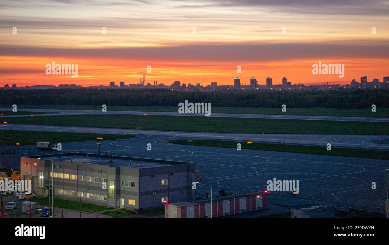 Pulkovo internationaler Flughafen und Start- und Landebahn in St. Petersburg, Russland mit dem schönen Sonnenuntergang, der den Himmel über der Silhouette der Stadt malt Stockfoto