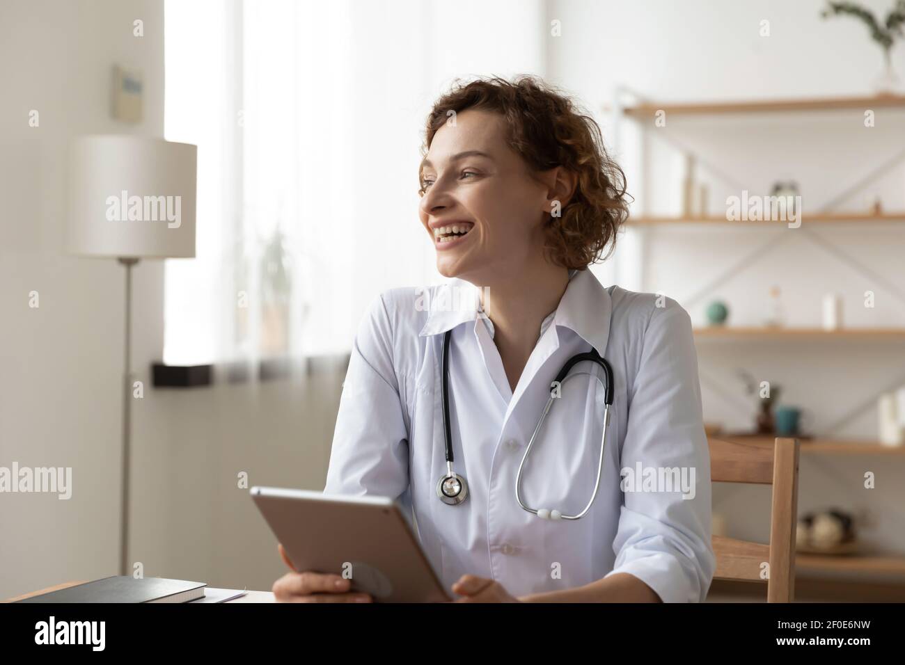 Lächelnd Arzt verwenden Tablette Blick in der Ferne Stockfoto