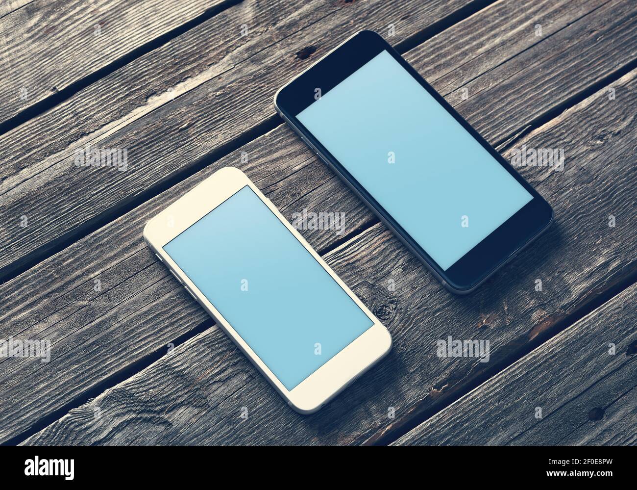 Zwei Mockup-Smartphones auf einem Holztisch Stockfoto