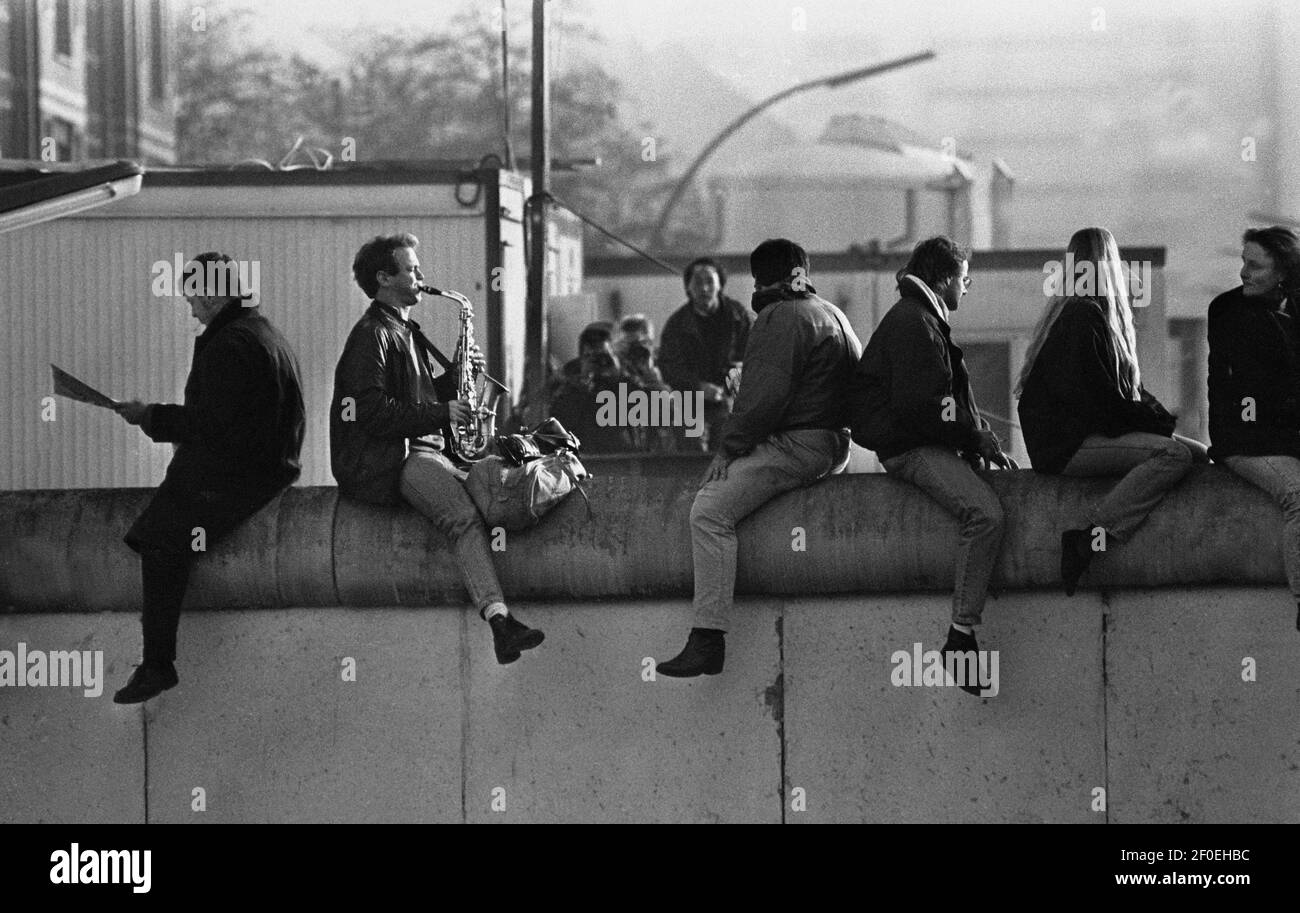 Berlin 12. November 1989. Blick von Osten nach Westen. Ein Ostberliner sitzt auf der Wand und spielt 'Misty' von Erroll Garner auf seinem Saxophon. Der Klang, der am ersten Sonntag nach dem Mauerfall in den ruhigen Straßen nachhallt. Die frühmorgendliche Wintersonne nahm die Kälte der Nacht weg. Ein schöner Morgen, erinnert 20 Jahre später. Wo ist der Saxophonspieler?COPYRIGHT FOTO VON BRIAN HARRIS 07808-579804 Stockfoto