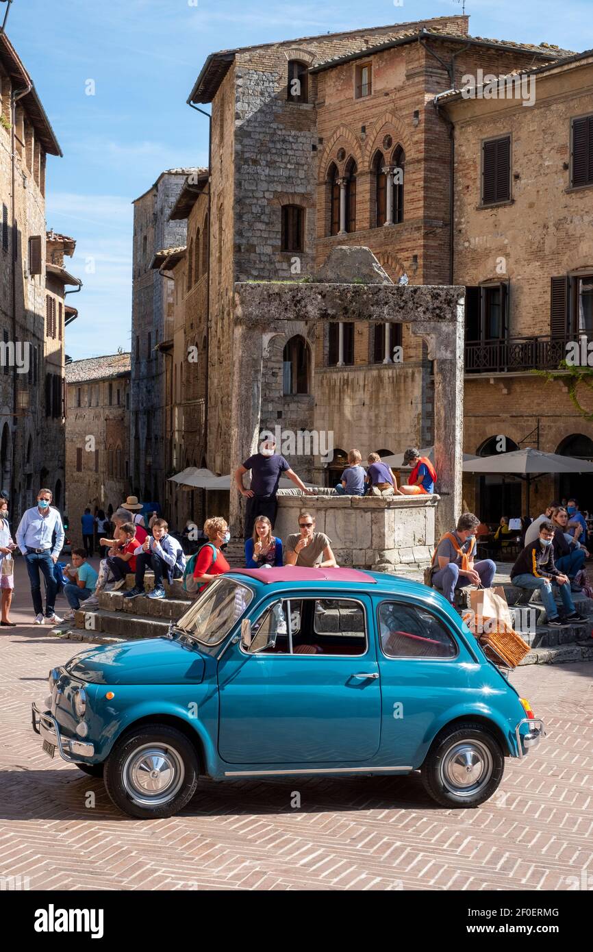 San Gimignano, Alte Fiat 500 auf dem Stadtplatz, umgeben von Menschen. Stockfoto