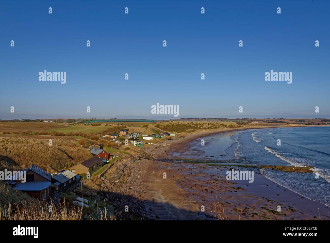 Die kleine Gemeinde Korbie Knowe schützte unter den Klippen am südlichen Ende der lunan Bay mit Blick auf den Sandstrand mit der Flut ausgehen. Stockfoto