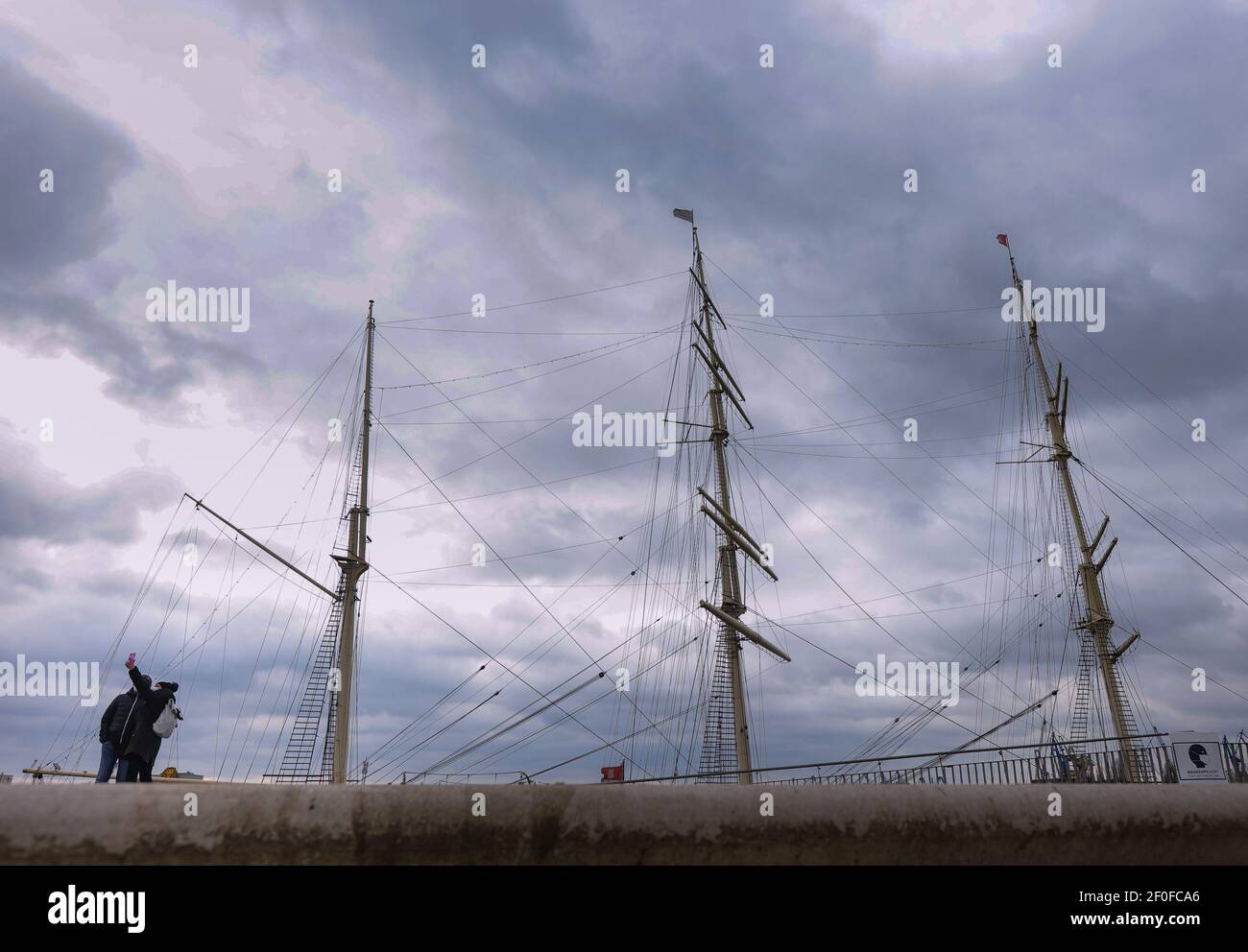 Hamburg, Deutschland. März 2021, 07th. Bei bewölktem Wetter fotografieren sich Touristen an der Elbpromenade in Hamburg vor einem historischen Segelschiff. Es wird erwartet, dass es in den kommenden Tagen in der Hansestadt bewölkt und kühl bleiben wird. Quelle: Ulrich Perrey/dpa/Alamy Live News Stockfoto