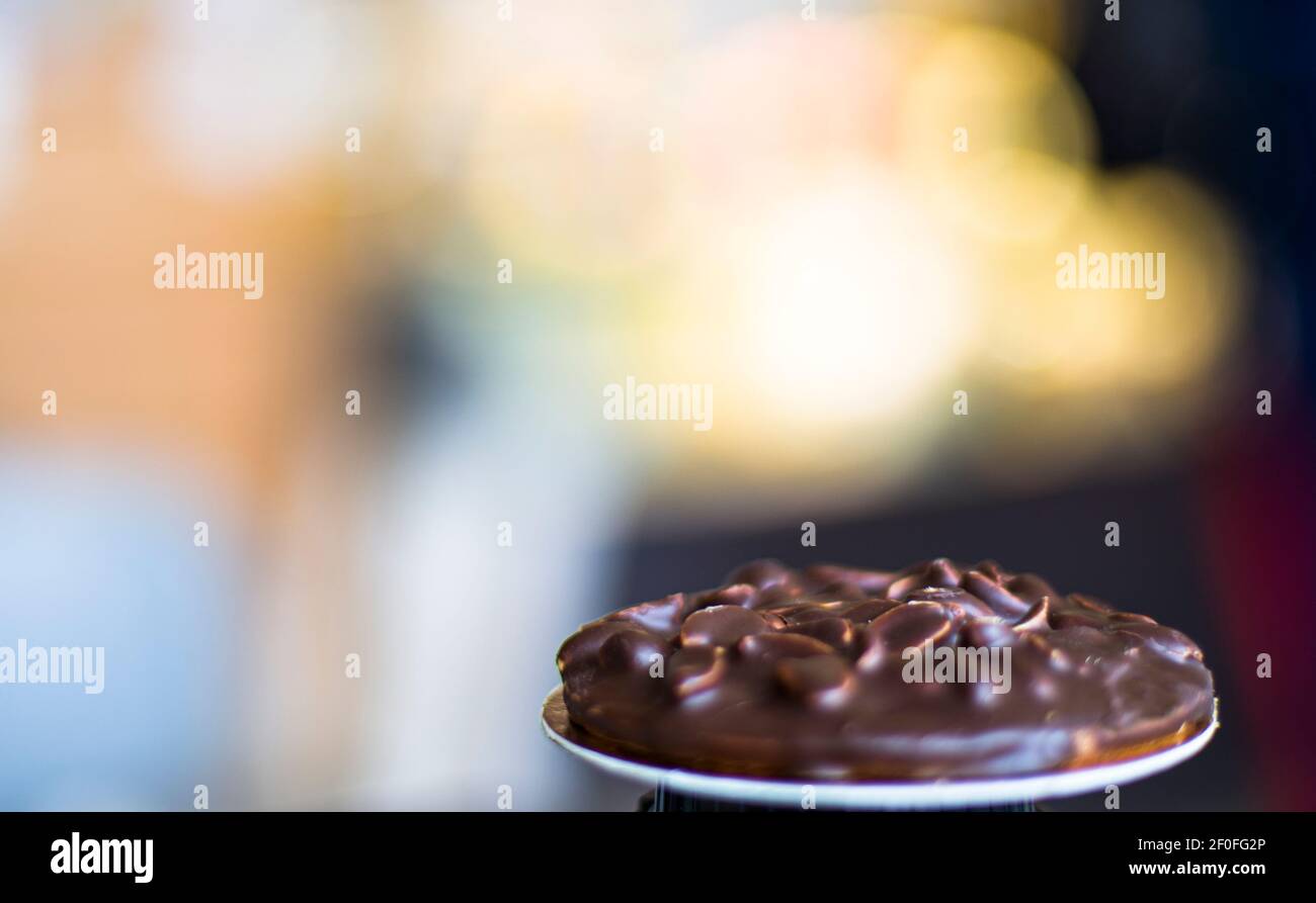 Ein schokoladenverglaster Erdnusskeks mit hellem Bokeh-Hintergrund Stockfoto