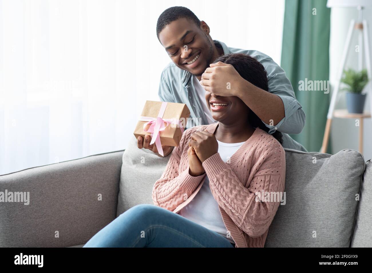 Afroamerikanischer Kerl, der seiner Freundin Geschenkbox gibt Stockfoto Afroamerikanischer Kerl, der seiner Freundin Geschenkbox gibt Stockfoto