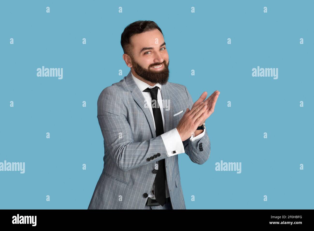 Portrait von glücklichen jungen Geschäftsmann geben Applaus, feiert Leistung auf blauem Studio-Hintergrund Stockfoto