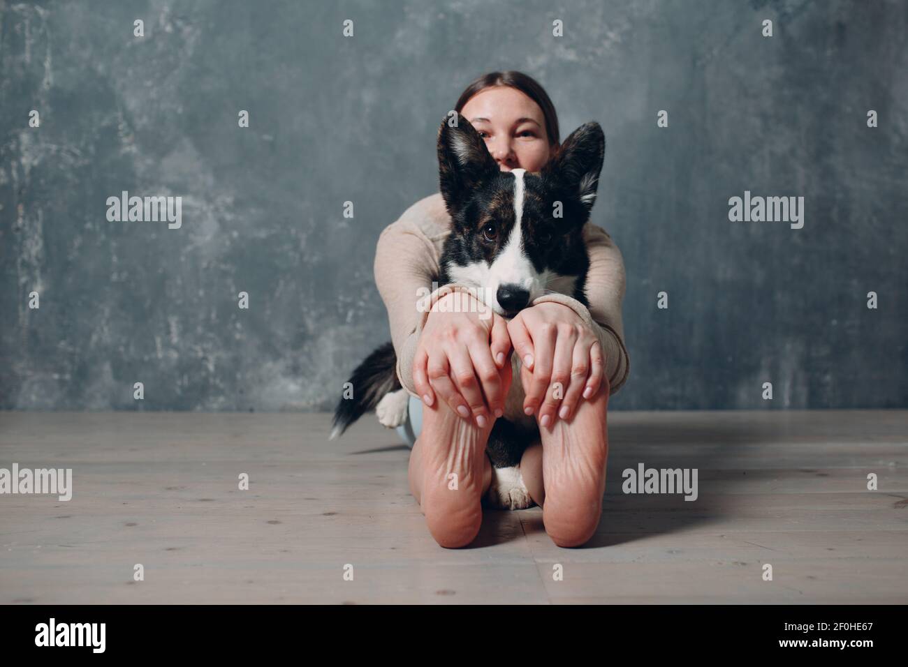 Junge Erwachsene Frau macht Yoga mit Corgi Hund zu Hause In Innenräumen Stockfoto