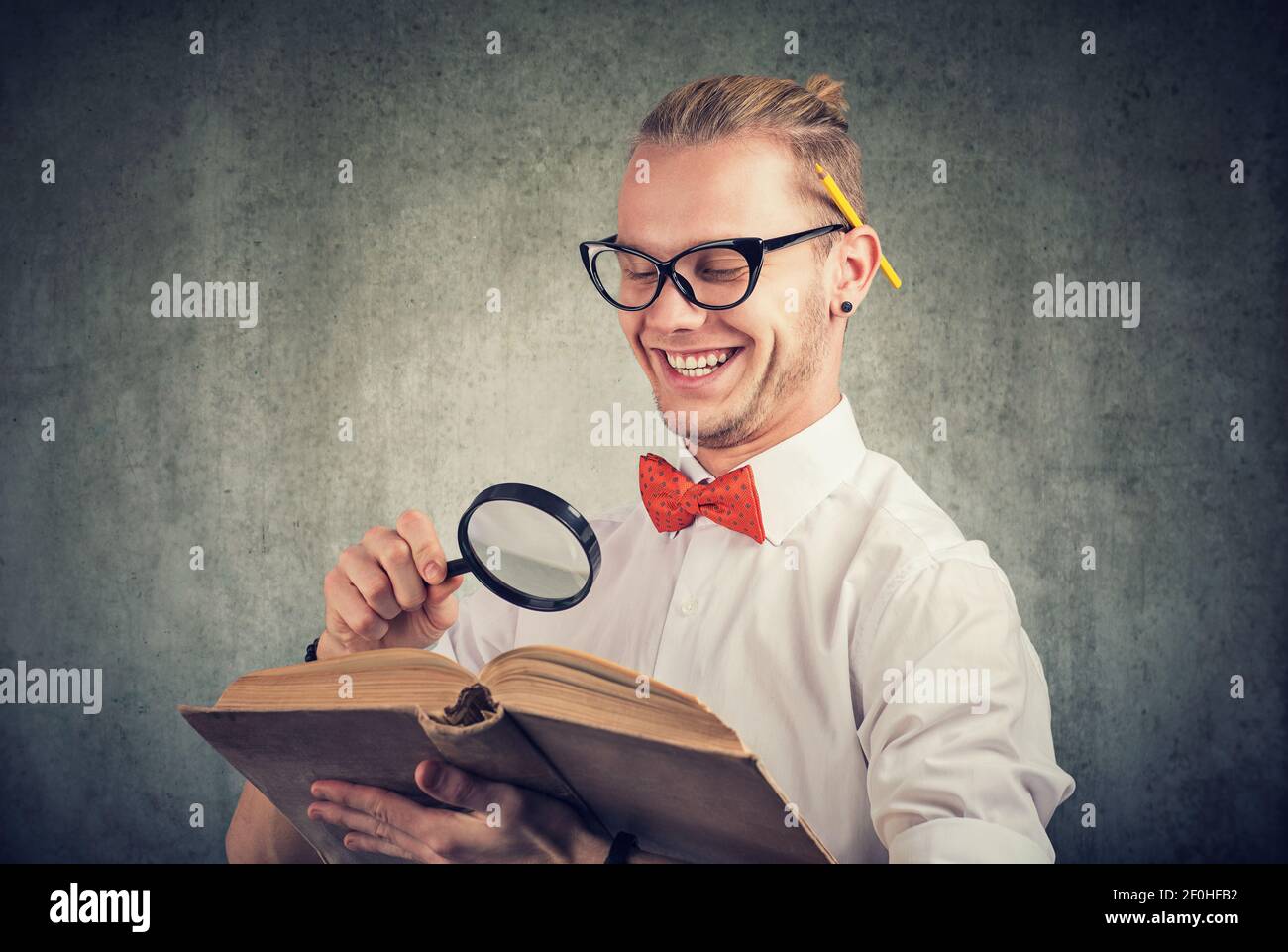 Portrait eines nerdy jungen Mannes, der ein altes Buch liest Stockfoto