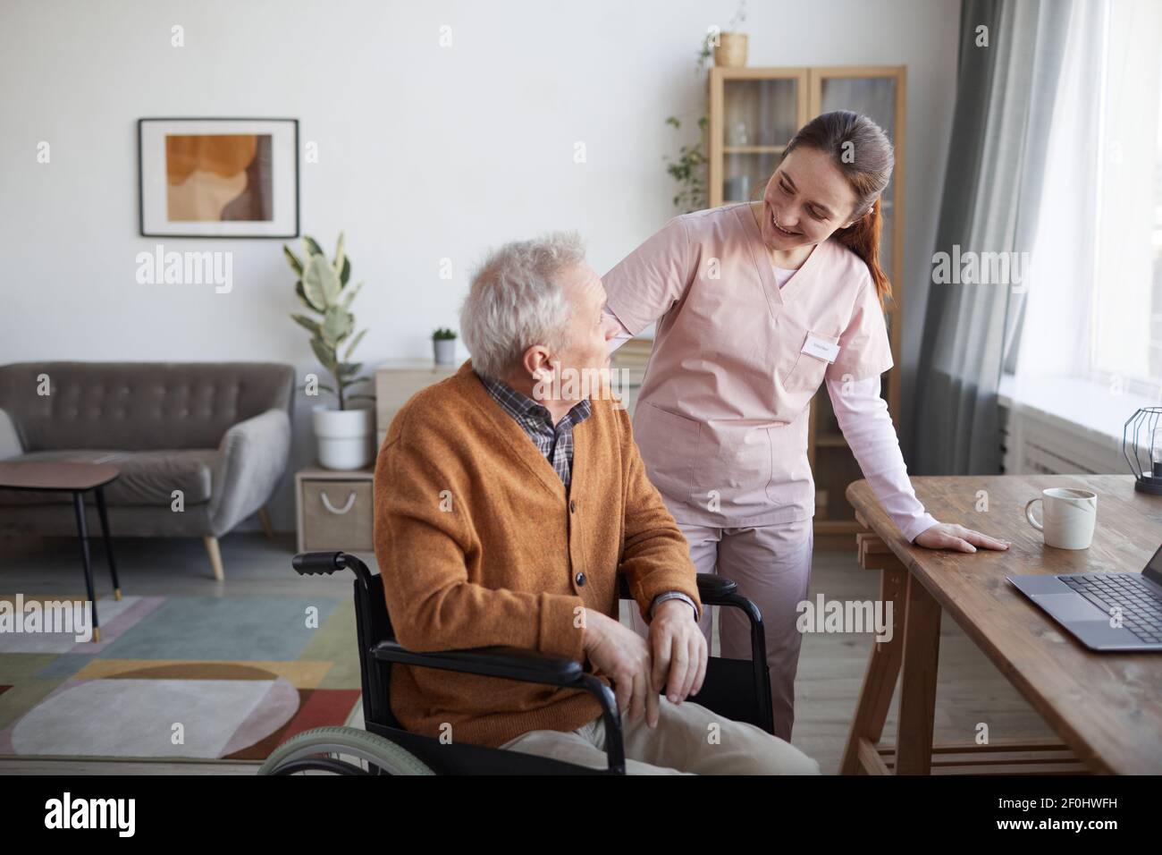 Porträt von lächelnden Krankenschwester hilft älteren Mann im Rollstuhl im Altersheim, kopieren Raum Stockfoto