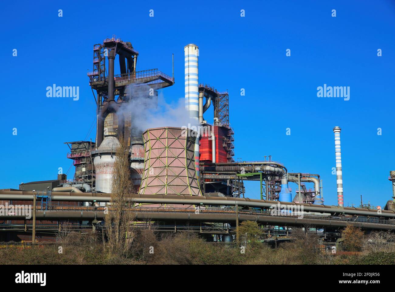 Duisburg (ruhrgebiet), Deutschland - März 1. 2021: Blick auf Industriekomplex mit rauchenden Schornsteinen und Turm gegen blauen Himmel - Thyssen Krupp Steel comp Stockfoto