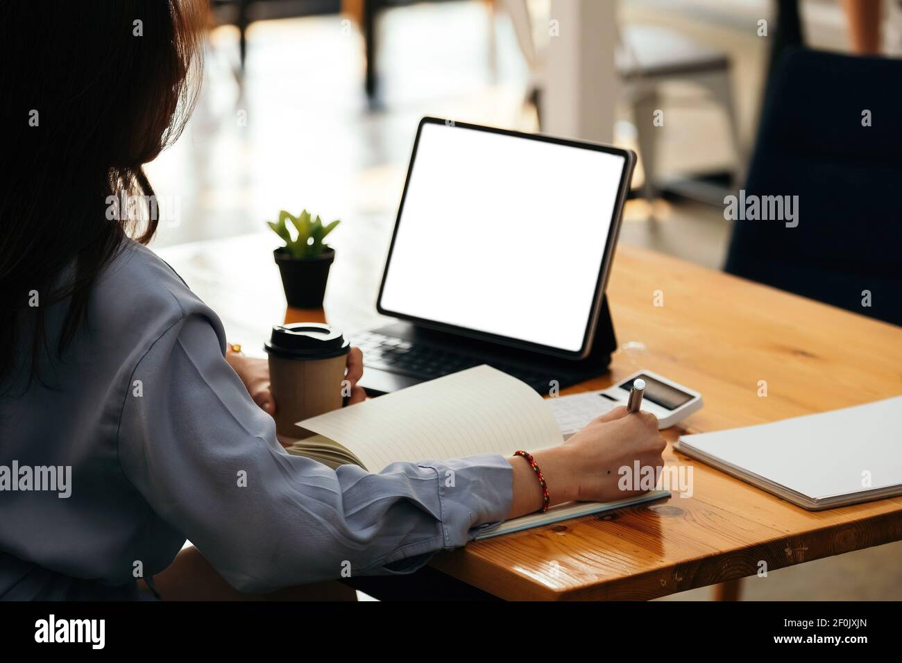 Geschäftsfrau handschriftlich auf Notebook, Arbeit auf Laptop-Computer mit Rechner auf dem Schreibtisch im modernen Home Office. Online arbeiten, zu Hause arbeiten Stockfoto