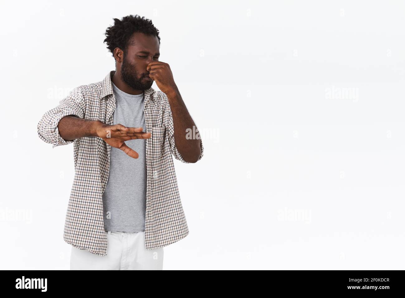 Kerl angewidert von schlechtem Geruch, Schritt zurück und beschirmen sich mit der Hand. afroamerikanisch bärtig Kerl decken Nase und schielen, griamace von stinken oder Stockfoto