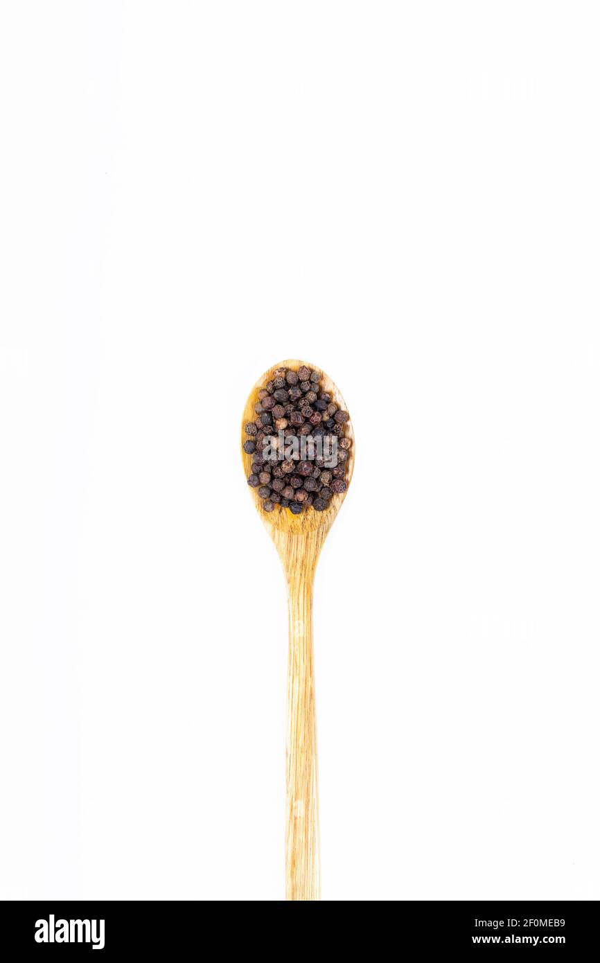 Schwarze Pfefferkörner (schwarzer Pfeffer) Samen in Holzlöffel isoliert auf weißem Hintergrund. Stockfoto
