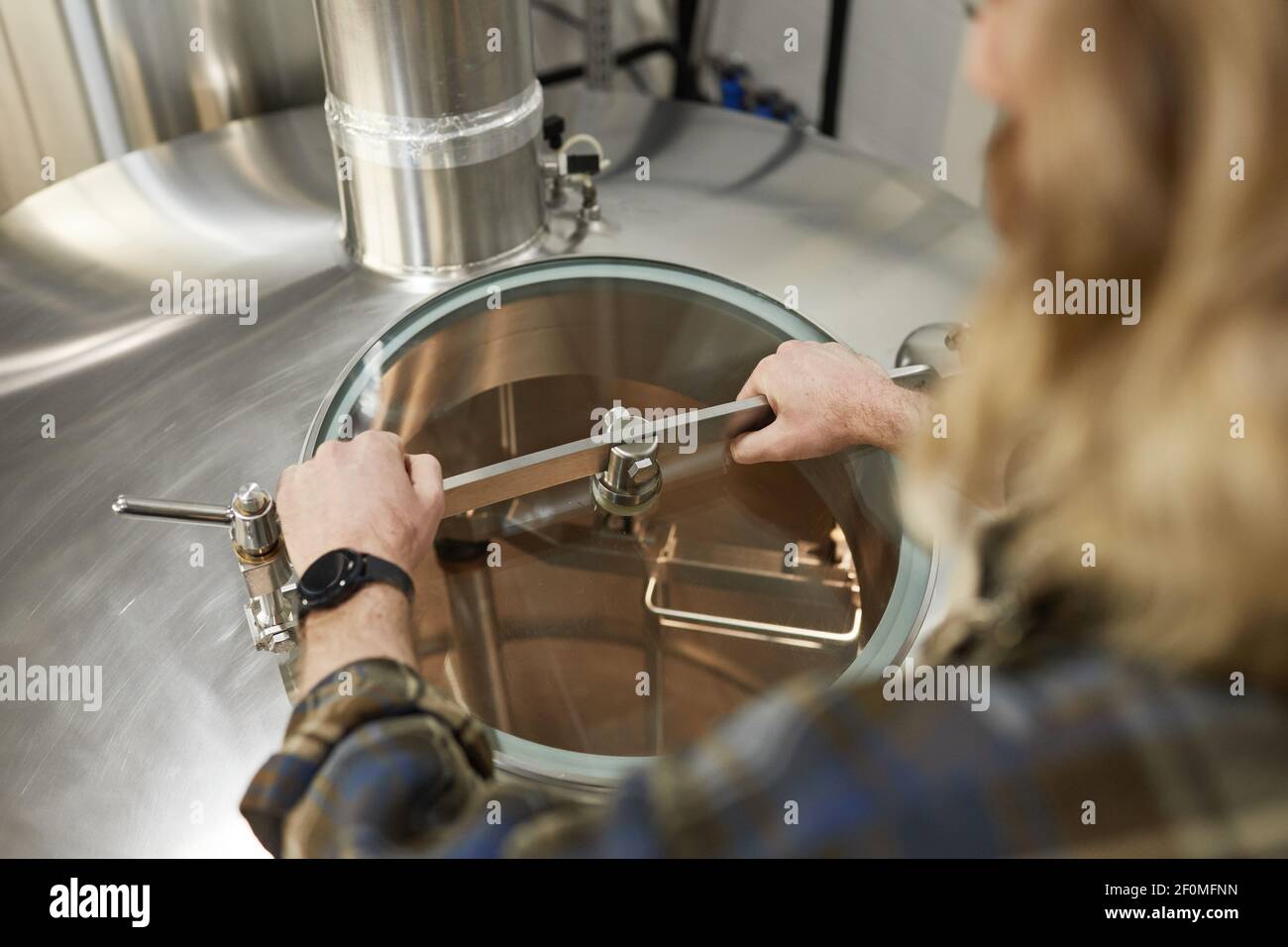 Nahaufnahme eines männlichen Arbeiters, der Tanks in der Brauerei öffnet, Bierherstellung, Kopierraum Stockfoto