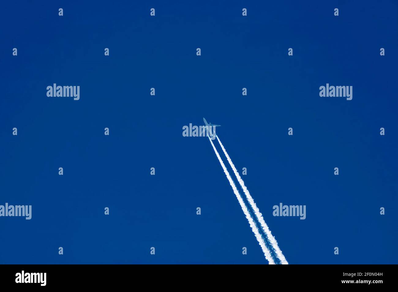 Jet-Flugzeug in den blauen Himmel mit weißen Spuren über dem Dorf Nisovo, Bulgarien Stockfoto
