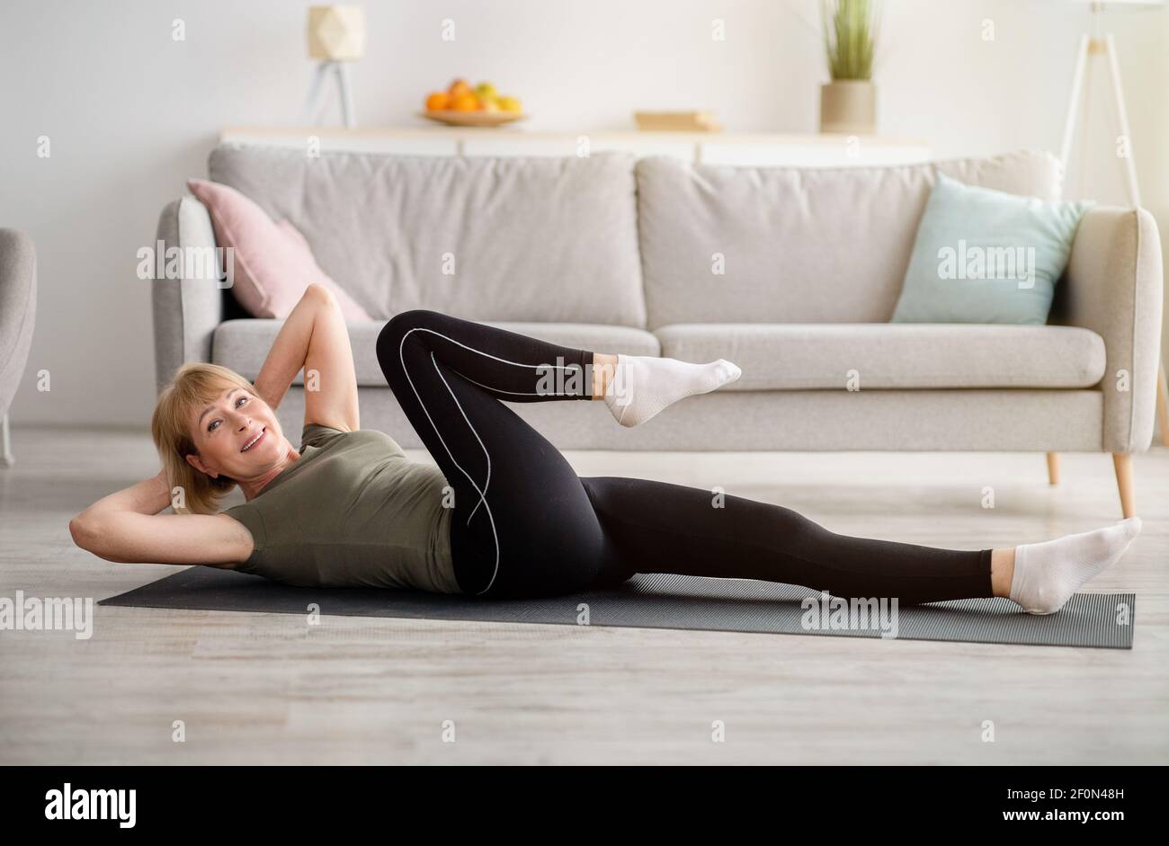 Fit Senior Frau macht abs-Übungen auf Yoga-Matte drinnen, leeren Raum. Krafttraining Konzept Stockfoto
