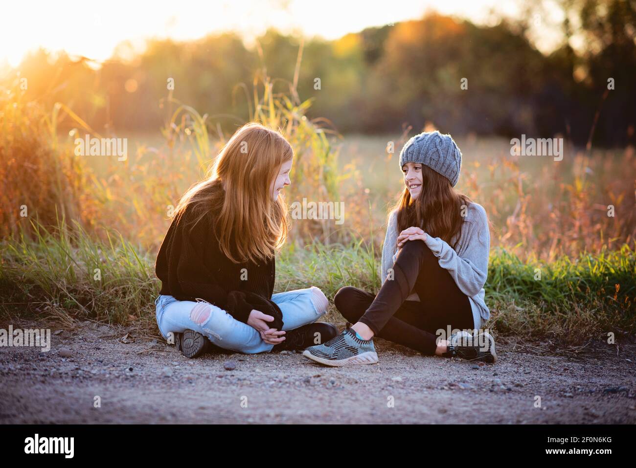 Zwei schöne junge Tween Mädchen in Pullover sitzen draußen im Herbst. Stockfoto