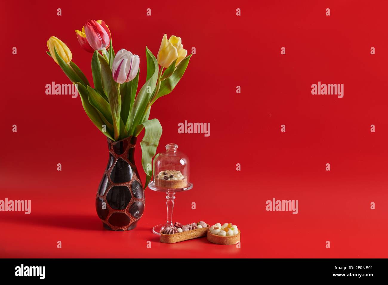 Bunte Blumen Tulpen auf einem roten Hintergrund Kuchen Stockfoto