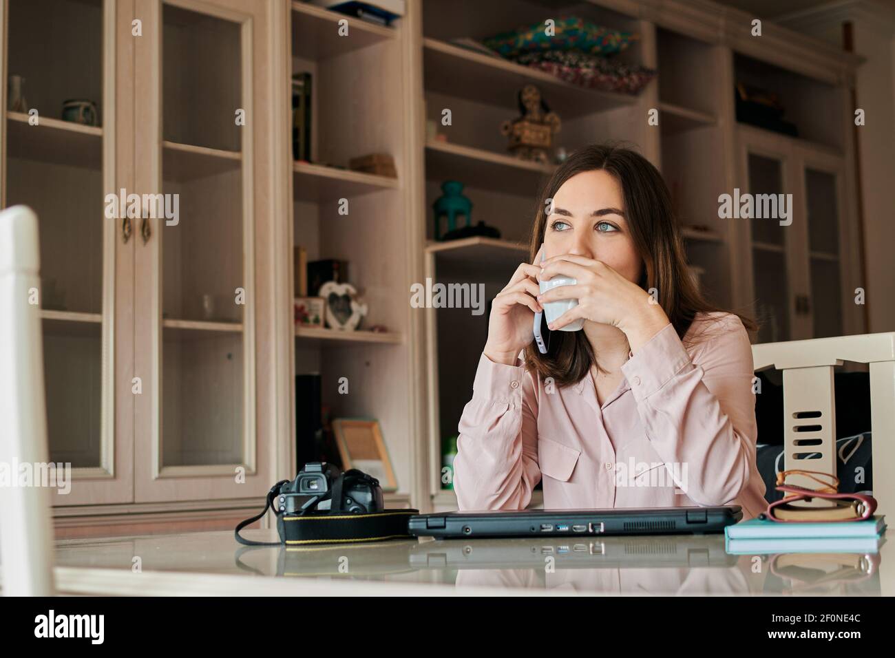 Die Frau trinkt Kaffee und spricht über sie Telefon von zu Hause aus Stockfoto