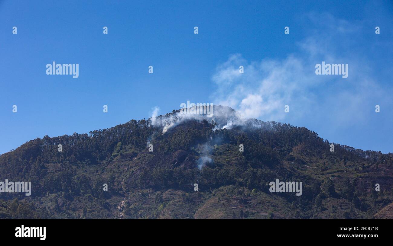 Rauch, der von einem Berggipfel durch Schrägstrich und emittiert Burn Landwirtschaft von Stammes Dorfbewohner praktiziert, wie während der Reise gesehen Auf der Palani Ghat Road Stockfoto