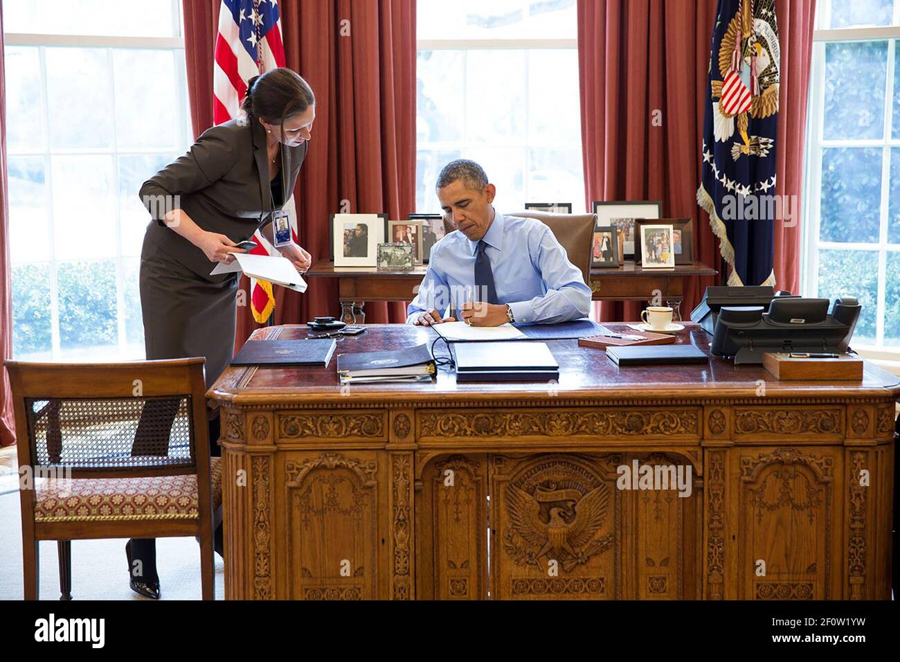 Präsident Barack Obama unterzeichnet zusammen mit dem Stabssekretär Joani Walsh Gesetzesvorlagen im Oval Office, 21. März 2014. Stockfoto