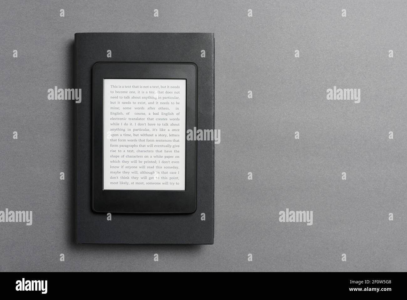 Elektronischer Leser mit Text auf dem Bildschirm über einem geschlossenen schwarzen traditionellen Buch, auf einem grauen Hintergrund. Konzepte von Technologie, Modernität und Lesen. F Stockfoto