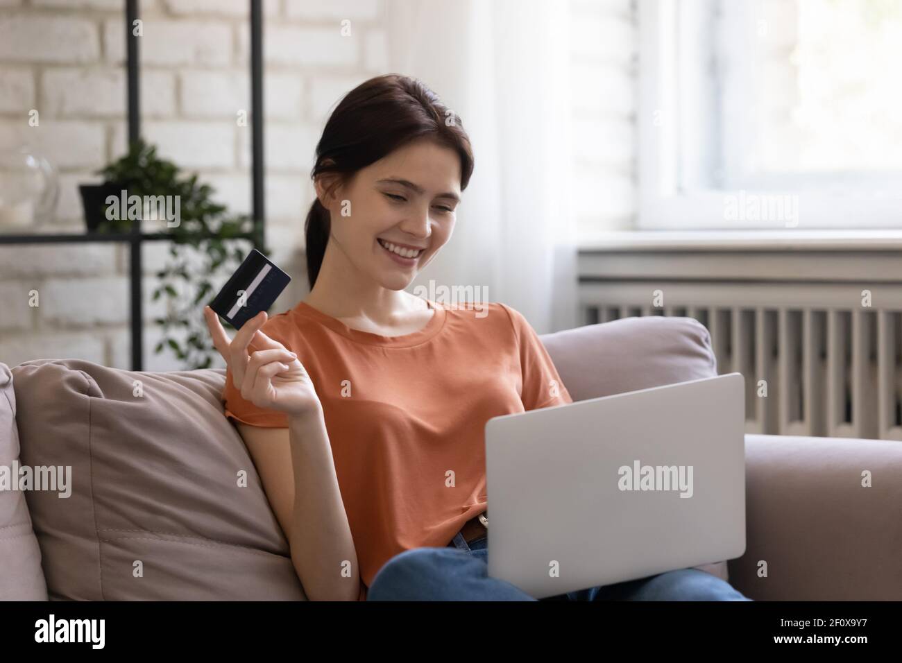 Glückliche Millennial Frau bezahlen für Waren online mit Kreditkarte Stockfoto