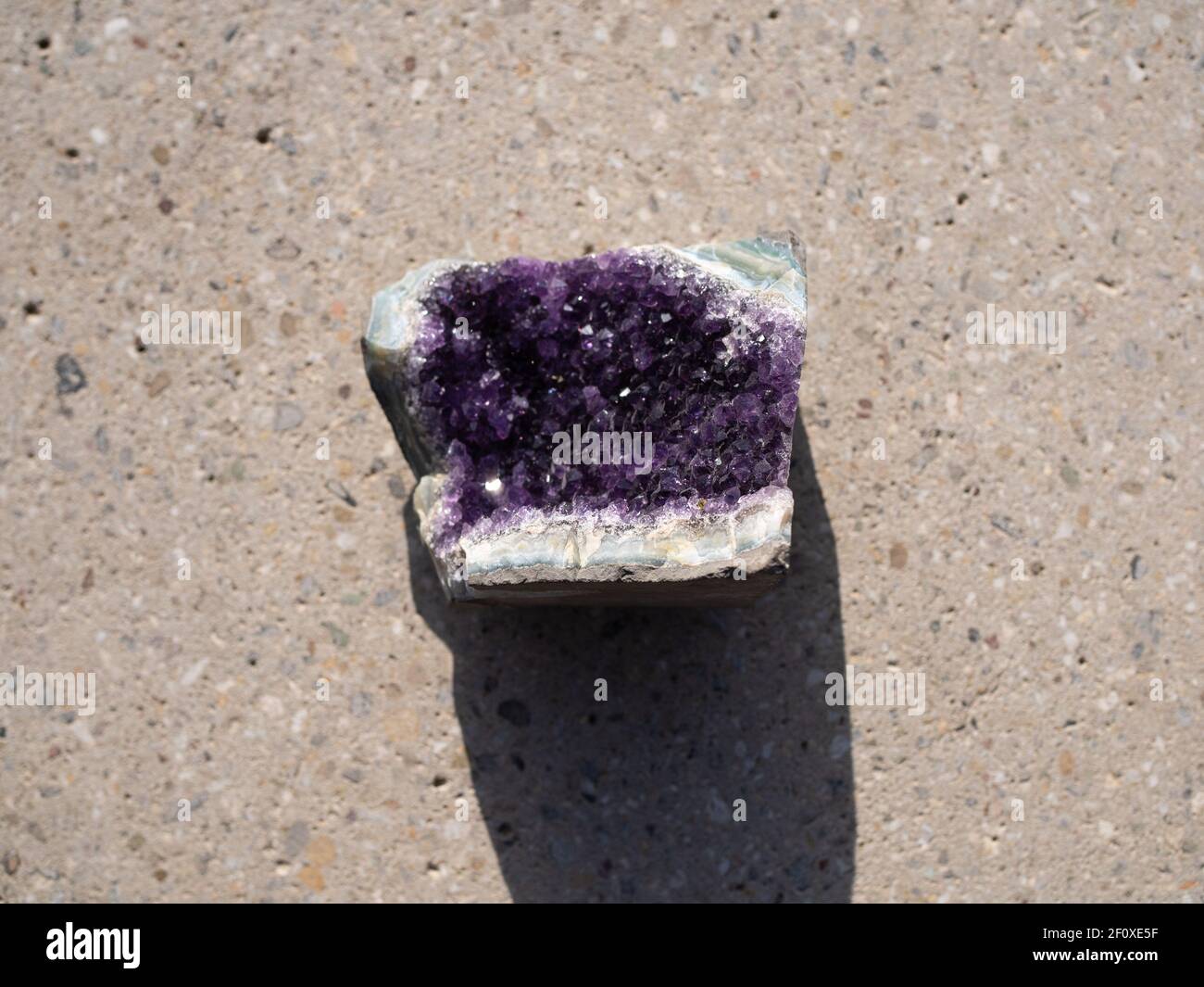 Amethyst-Mineralstein auf Betonoberfläche. Stockfoto