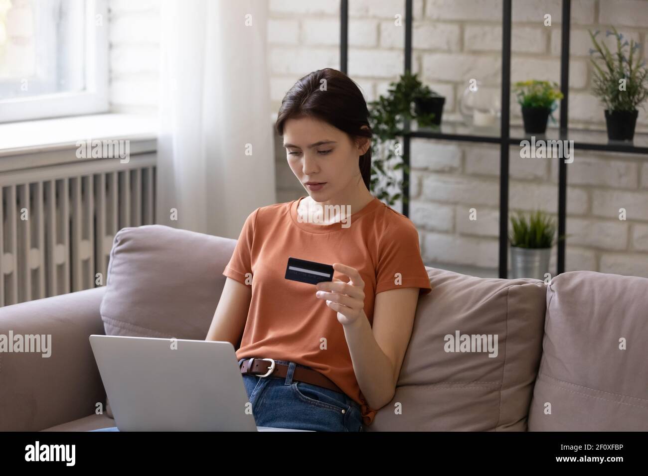 Fokussierte weibliche Shopper halten Karte Studie Website, bevor die Zahlung bestätigen Stockfoto