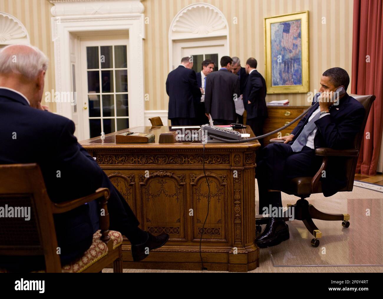 Präsident Barack Obama telefoniert mit dem ägyptischen Präsidenten Hosni Mubarak im Oval Office Jan. 28 2011. Vizepräsident Joe Biden verließ und das Nationale Sicherheitsteam des Präsidenten hörte im Hintergrund zu. Stockfoto
