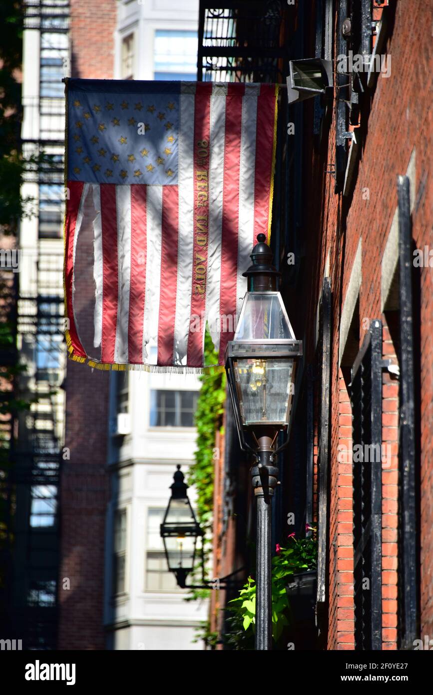 Betsy Ross Flagge hängt über den kolonialen Hausfronten entlang Acorn St. in Boston mit Backstein und Streelight-Features. Stockfoto