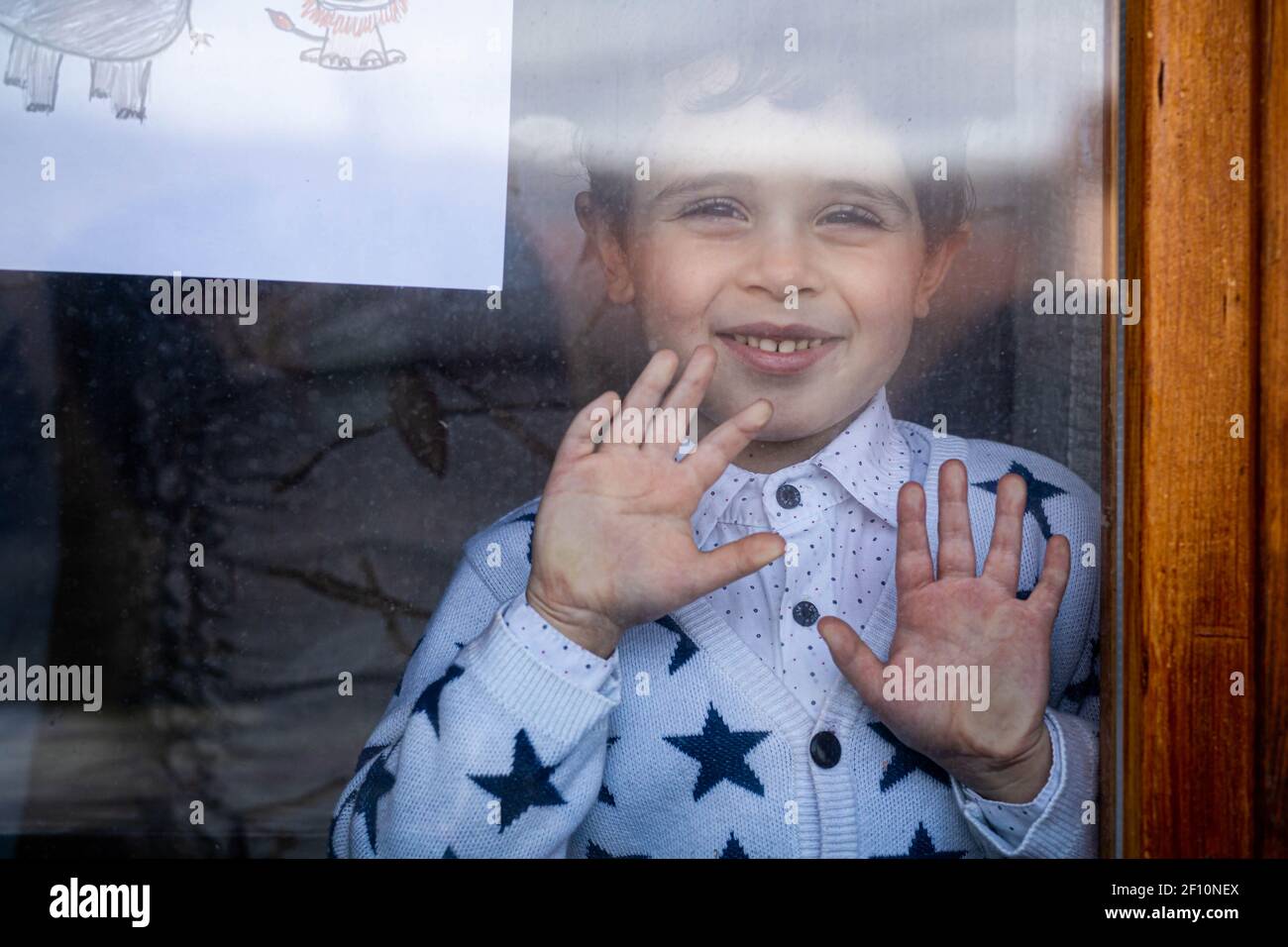 Netter kleiner Junge, der von innen durch das Fenster schaut Stockfoto