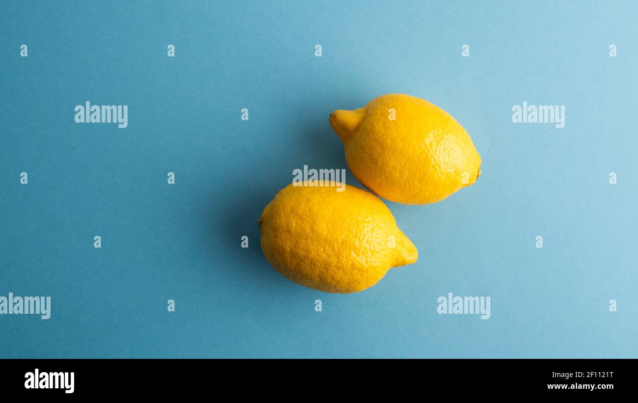 Zitronen, zwei gelbe Zitrone auf grauem Hintergrund. Blick von oben. Stockfoto