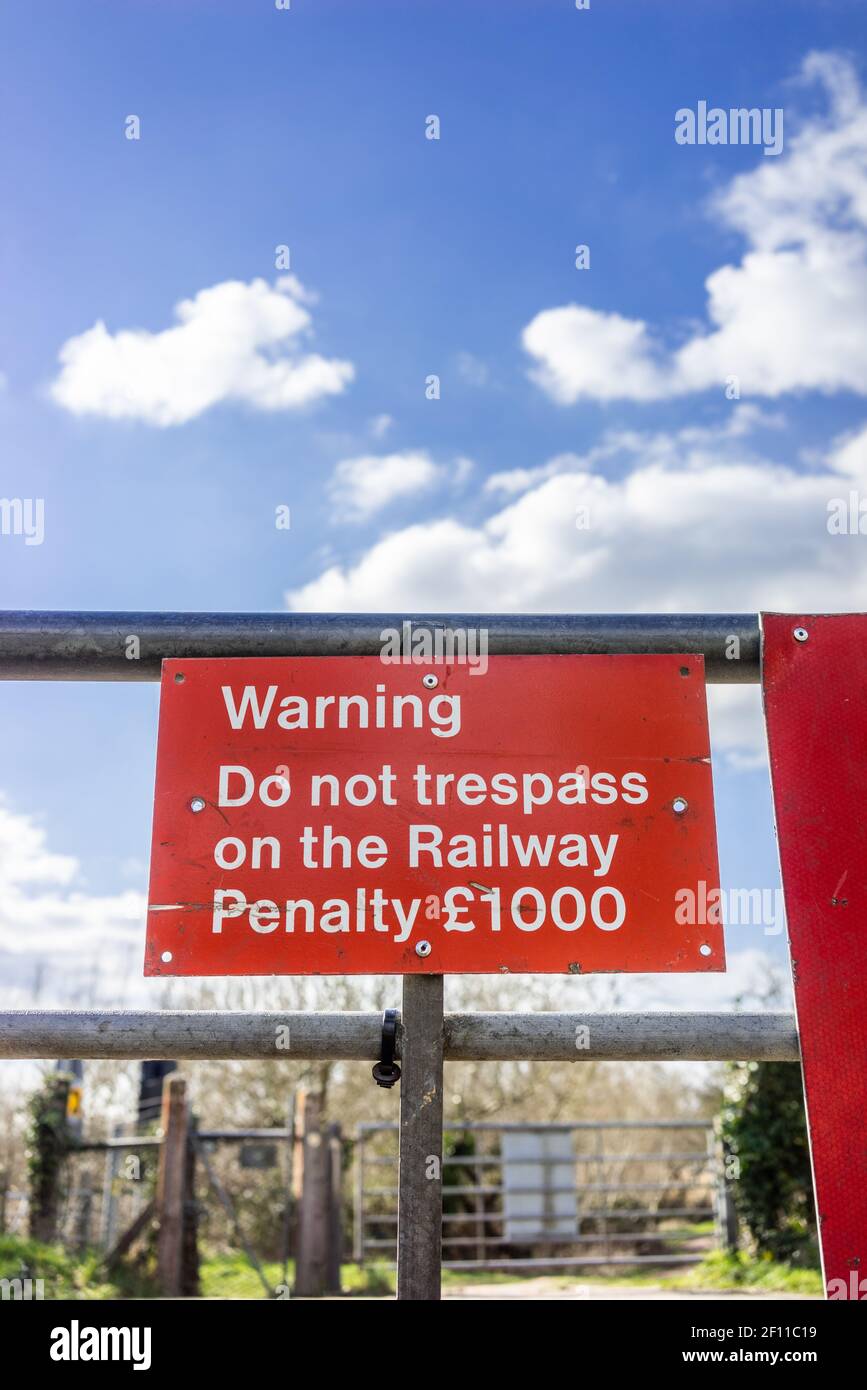 Red Stop Achtung Trespass nicht Warnschild an einem Tor an einem Bahnübergang in Südengland, Großbritannien Stockfoto