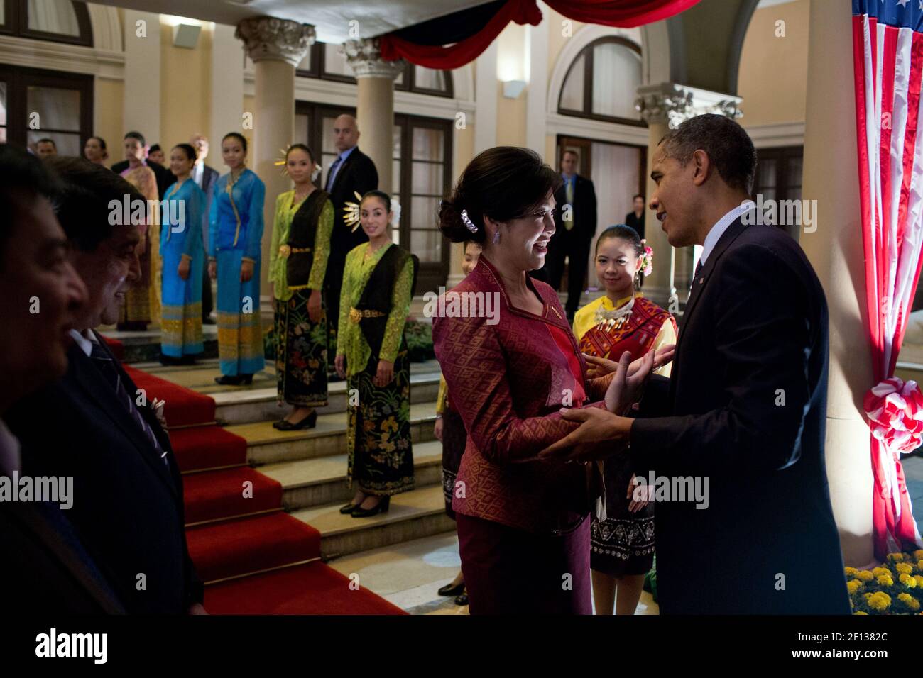 Präsident Barack Obama spricht mit dem thailändischen Premierminister Yingluck Shinawatra, bevor er am 18 2012. November das Regierungsgebäude in Bangkok, Thailand, verlässt. Thailändische Begrüßungskünstler säumen die Treppen. Stockfoto