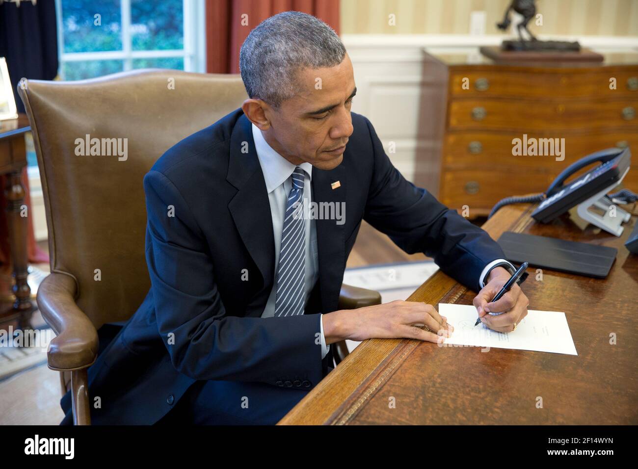 Präsident Barack Obama unterzeichnet einen Brief an kubanischen Briefeschreiber, im Oval Office, 14. März 2016. Stockfoto